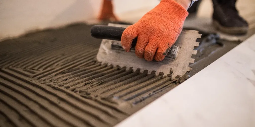 laying ceramic tiles troweling mortar onto concrete floor preparation laying white floor tile